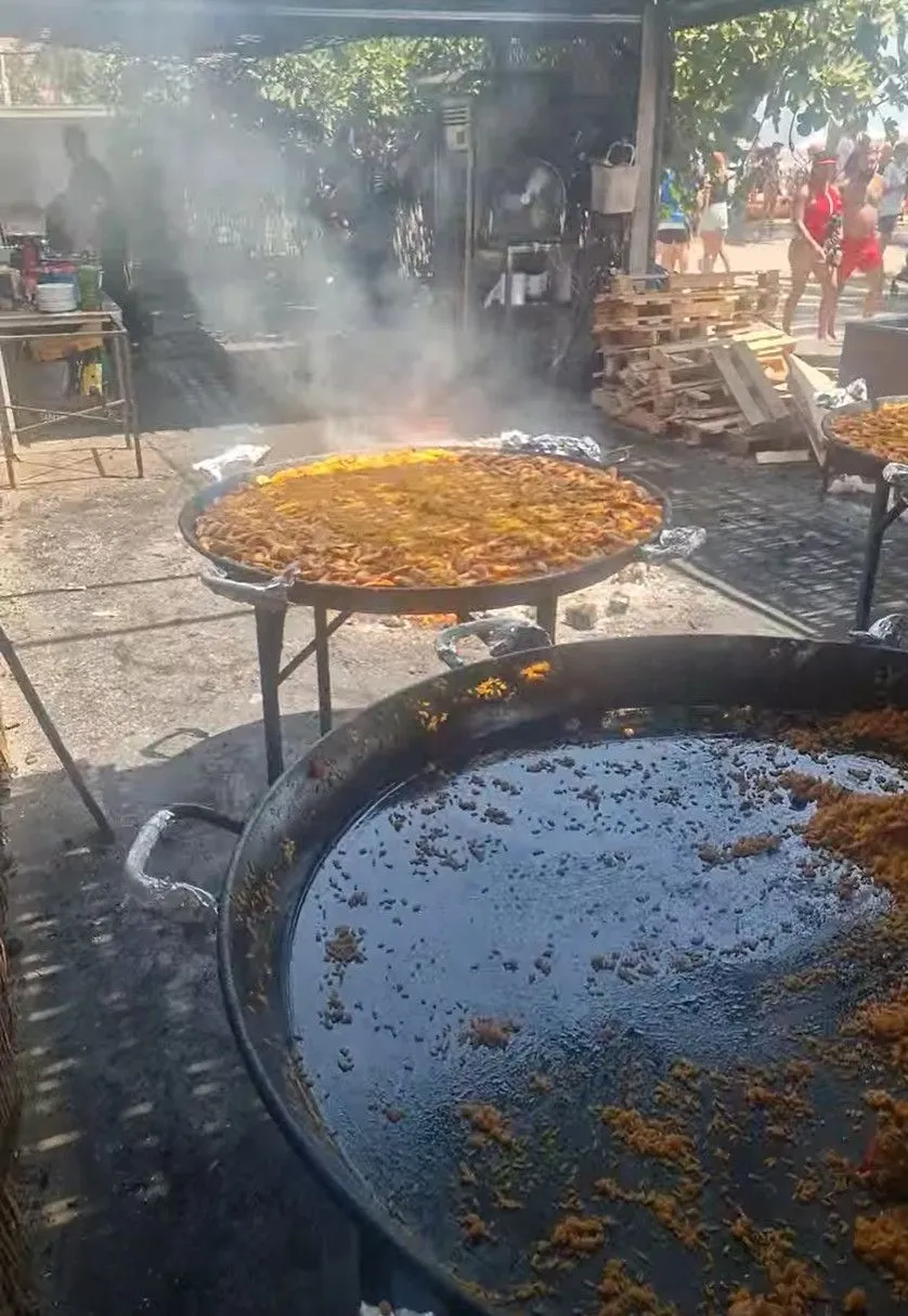 Two huge paella pans cooking over an open fire at Chiringuito Ayo on Playa Burriana, Nerja